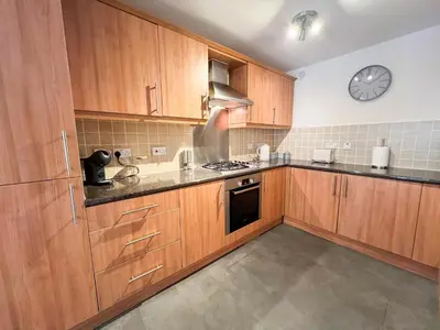 a kitchen with wooden cabinets and a clock on the wall at Duplex Apartment in Glasgow in Glasgow