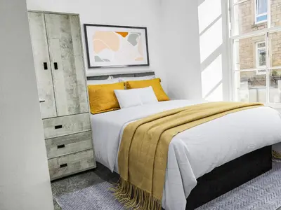 a bedroom with a large bed and a dresser at Hamish Apartment in Stirling
