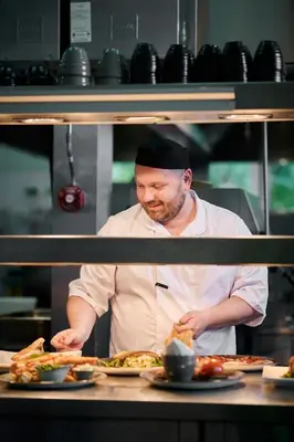 a chef preparing food in a restaurant kitchen at Stirling Highland Hotel- Part of the Cairn Collection in Stirling
