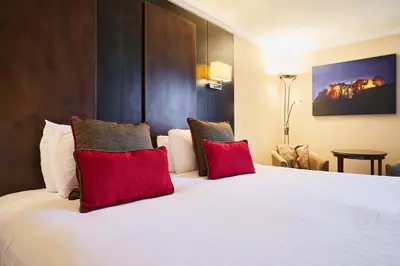 a bedroom with a large white bed with red pillows at Stirling Highland Hotel- Part of the Cairn Collection in Stirling