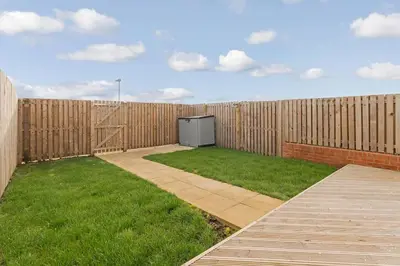 a backyard with a wooden fence and a television at Scenic getaway, open plan home! 2bed park for free in Eaglesham