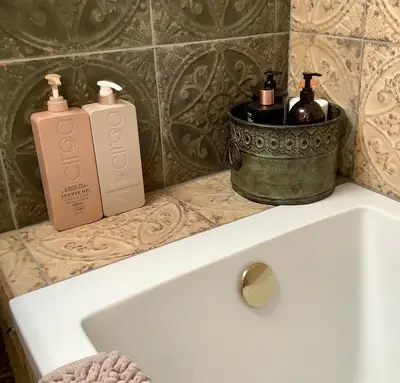 two bottles of soap sitting on top of a bath tub at Holmlea Cottage in Moffat