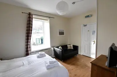 a bedroom with a bed and a chair and a window at Argyll House Pennyghael in Salen