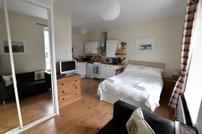 a bedroom with a white bed and a kitchen at Argyll House Pennyghael in Salen