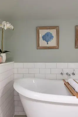 a white bath tub in a bathroom with a picture at The Coach House, Pentland Hills in Nine Mile Burn