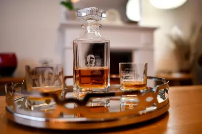 a bottle of whiskey and two glasses on a tray at Ladyland Cottage in Maybole in Maybole