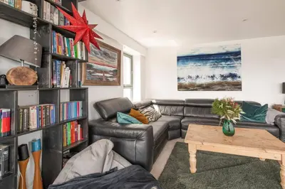 a living room with a couch and a book shelf at Calming Sea View City Apartment in Edinburgh
