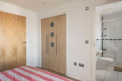 a bedroom with a wooden door and a bathroom at Calming Sea View City Apartment in Edinburgh