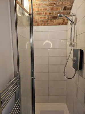 a shower with a glass door in a bathroom at The Armoury: Stylish WW1 Bunker in North Queensferry