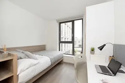 a white bedroom with a bed and a desk with a laptop at For Students Only St Mungo's in Glasgow in Glasgow