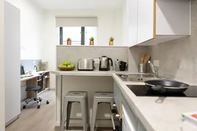 a kitchen with a sink and a counter with stools at For Students Only St Mungo's in Glasgow in Glasgow