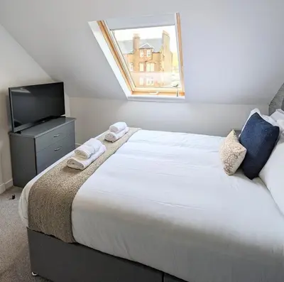 a bedroom with a large white bed and a television at Erradale in Campbeltown