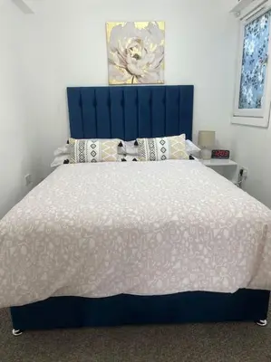 a bedroom with a large bed with a blue headboard at Penlea ~ 1 bedroom Flat with Harbour view in Tarbert