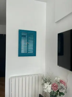 a white wall with a blue window and a vase of flowers at Penlea ~ 1 bedroom Flat with Harbour view in Tarbert