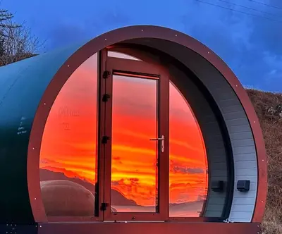 a dome house with a sunset in the window at Port Nan Gael Pods in Pennyghael