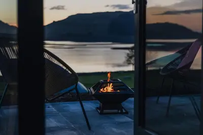a fire pit on a patio with a view of the water at Port Nan Gael Pods in Pennyghael