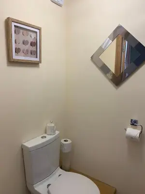 a white bathroom with a toilet and a mirror at Lakeview Guest House in Stranraer