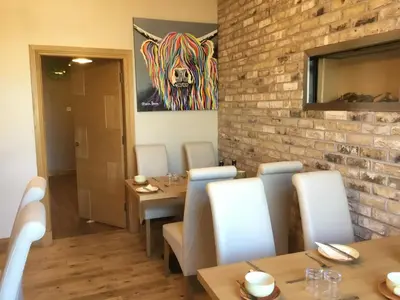 a dining room with a table and chairs and a brick wall at Lakeview Guest House in Stranraer