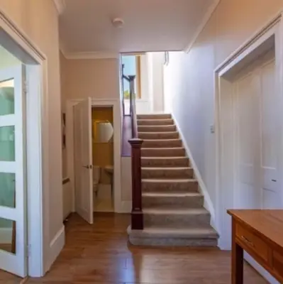 a staircase in a home with white walls and wooden floors at Room 1, Loch Etive House, Connel near Oban in Connel