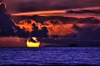 a sunset over the ocean with a ship in the distance at Pirnmill Home with a view in Pirnmill