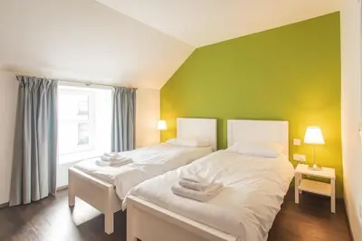 two beds in a room with a green wall at The Saddlers House - best price per bed in Bowmore