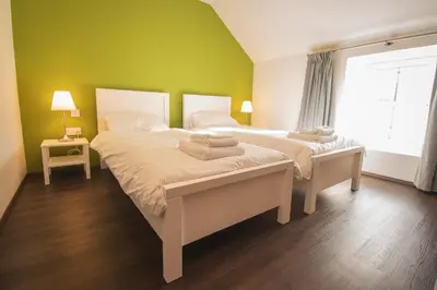 two beds in a bedroom with a green wall at The Saddlers House - best price per bed in Bowmore