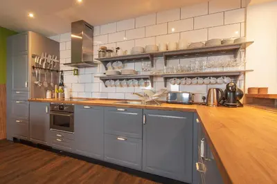 a kitchen with gray cabinets and a wooden counter top at The Saddlers House - best price per bed in Bowmore