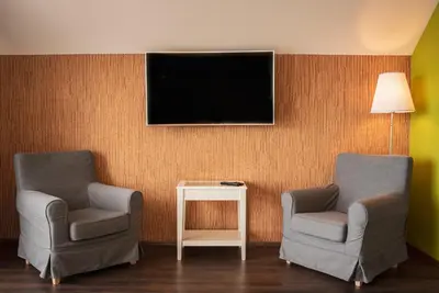 a room with two chairs and a tv on a wall at The Saddlers House - best price per bed in Bowmore