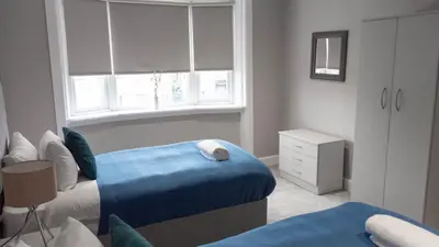 a bedroom with two beds and a window at Castlemilk Apartment in Glasgow