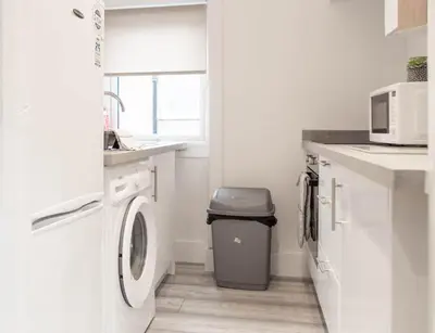 a white laundry room with a washer and dryer at Castlemilk Apartment in Glasgow