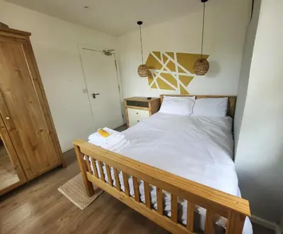 a bedroom with a large bed with a wooden frame at Mini hotel with home facilities in Hamilton West in High Blantyre