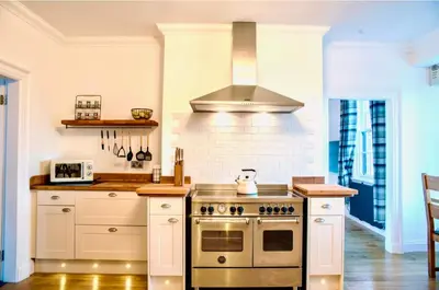 a kitchen with white cabinets and a stove top oven at Gleddoch Coach House in Langbank
