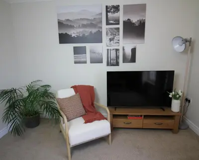 a living room with a tv and a chair and a table at Island View - Spacious Two Bedroom Oban Apartment with Sea Views in Oban