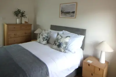 a bedroom with a bed with pillows and a night stand at Island View - Spacious Two Bedroom Oban Apartment with Sea Views in Oban