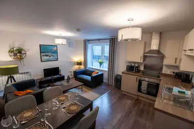 a living room with a dining table and a kitchen at Bowmore Apartment in Oban