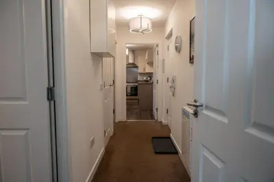 a hallway leading to a kitchen with white cabinets at Bowmore Apartment in Oban