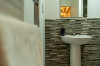 a bathroom with a sink and a mirror at Bowmore Apartment in Oban