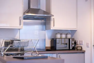 a kitchen with white cabinets and a counter with a microwave at Jura Apartment in Oban