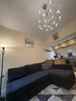 a living room with a blue couch and a chandelier at One Bedroom Flat in Central Edinburgh Old Town , Heart of Edinburgh Flat Sleeps 4 in Edinburgh