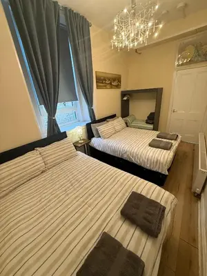 a bedroom with two beds and a chandelier at One Bedroom Flat in Central Edinburgh Old Town , Heart of Edinburgh Flat Sleeps 4 in Edinburgh