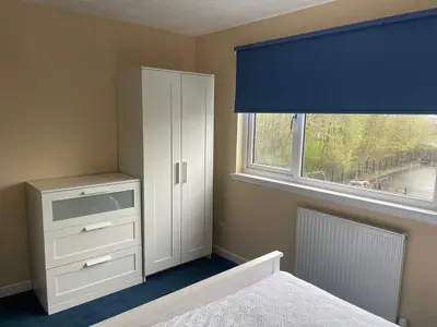 a bedroom with a white cabinet and a window at Gateway to the Loch in Balloch