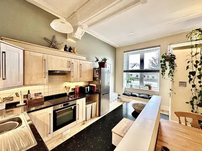 a large kitchen with wooden cabinets and a living room at 1 The Cairn Kilmartin - Beautiful Victorian Flat, Pet Friendly in Kilmartin