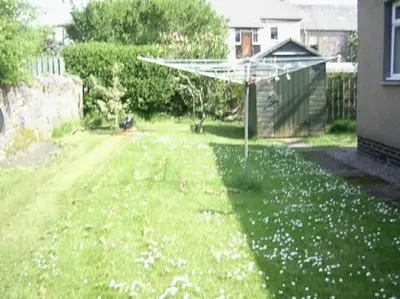 a garden with a sprinkler in the middle of a yard at Garden Cottage Helensburgh in Helensburgh
