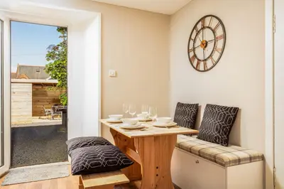 a dining room with a table and chairs and a clock on the wall at South Beach View in Troon