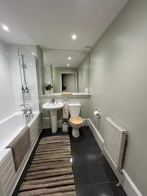 a bathroom with a sink and a toilet and a mirror at Acorn House Callander in Callander