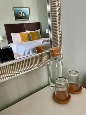 a bottle of water and glasses on a table in front of a mirror at Acorn House Callander in Callander