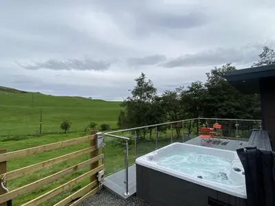 a hot tub on a balcony with a view of a field at Laigh Letterpin Lodge in Girvan