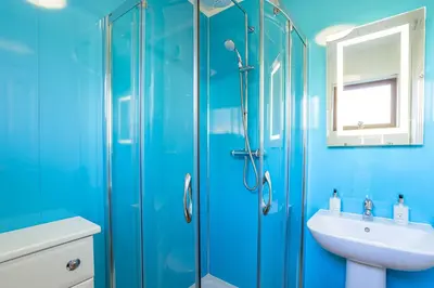 a blue bathroom with a sink and a shower at Birch Lodge in Newton Stewart