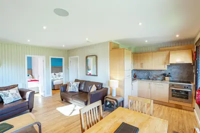 a kitchen and living room with a couch and a table at Birch Lodge in Newton Stewart