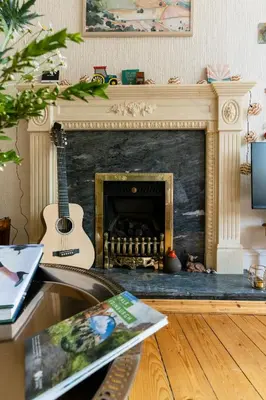 a living room with a guitar and a fireplace at Palm Tree Apartment- Period Home with Cat in Edinburgh
